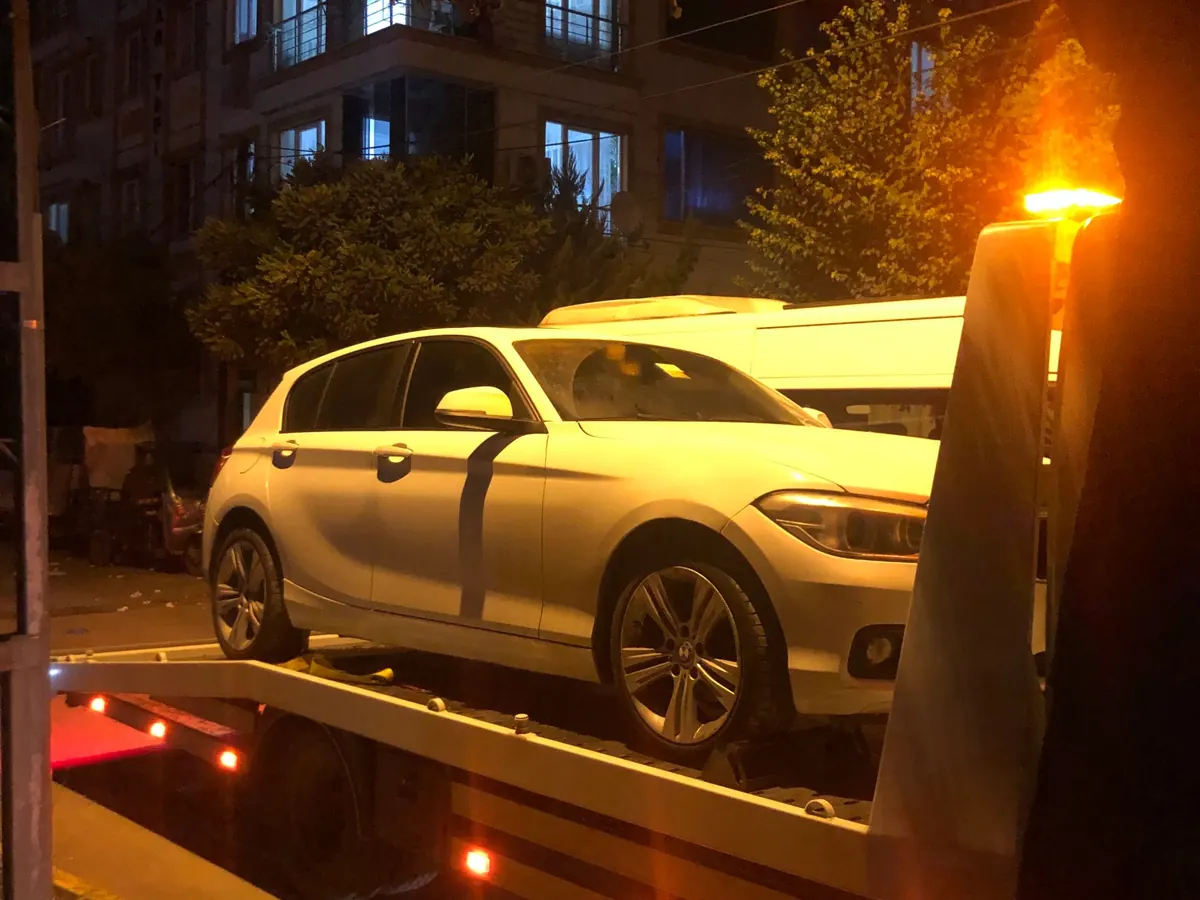 Gece uyarı lambası yanan çekici üzerinde beyaz hatchback