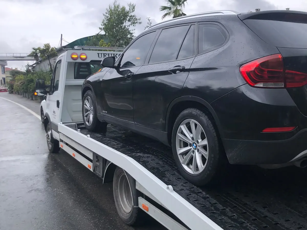 Yağmurlu havada kayar kasa çekici üzerinde taşınan siyah SUV